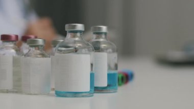 Laboratuvarda şeffaf sıvı şişeleri olan 19 aşıyı kapatın..