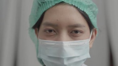 COVID-19 salgını sırasında hastanede çalışan yüzü maskeli, tıbbi koruma üniformalı Asyalı hemşire..