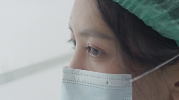 窓の外を見ている若い女性看護師は仕事から疲れている厳しいCovid 19パンデミックの状況のために — ストック動画