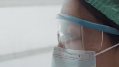 Coronavirus salgını sırasında hastanede dinlenirken yorgun düşmüş ve pencereden dışarı bakan bir doktor ya da hemşire..