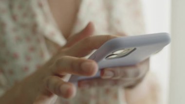 Evdeki oturma odasında dururken sosyal medyada telefon yazarak mesaj yazan kadını kapat.