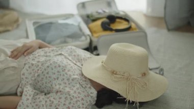 Seyahat eden Asyalı kadın yaz tatili için bavul hazırladıktan sonra dinleniyor..