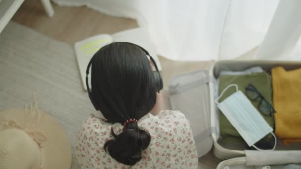 Путешествуйте Азиатская Девушка Лежит Полу Спальне Читая Книгу Слушая Музыку — стоковое видео