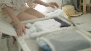 Yatak odasında seyahat eden Asyalı bir kadın, bavul hazırlıyor yaz tatiline hazırlanıyor..