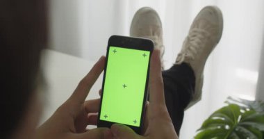 Ofis odasında krom tuşlu yeşil ekranlı akıllı telefon kullanarak sosyal medyada gezinen ya da çevrimiçi içeriği, iletişim konseptini izleyen bir iş adamı. Görüntüyü Kapat.