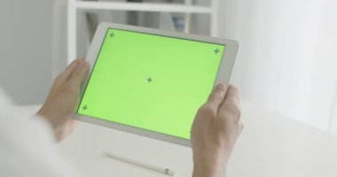 Ofis odasında krom anahtar yeşil ekranlı tablet kullanarak bir sandalyeye oturan Asyalı işadamını kapat, sosyal medyada kaydır veya çevrimiçi içerik, iletişim konsepti izle.