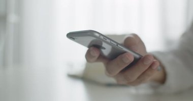 Ofis odasında bir sandalyede oturan, sosyal medyada kaydırma yapan bir akıllı telefon kullanan ya da online içerik, iletişim konsepti izleyen yakın plan bir adam..