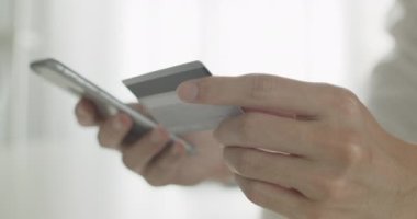 İşadamı evdeki ofis odasında e-ticaret alışveriş konseptinde otururken kredi kartı ödemesi parasıyla akıllı telefondan online alışveriş yapıyor. Görüntüyü Kapat.
