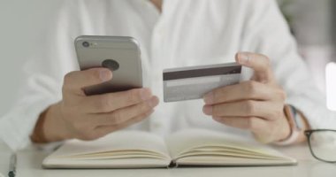 İşadamı evdeki ofis odasında e-ticaret alışveriş konseptinde otururken kredi kartı ödemesi yaparak akıllı telefondan alışveriş yapıyor..