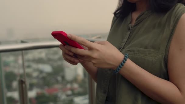 在日落时分 女人们站在公寓楼顶的阳台旁 用智能手机检查社交媒体 与朋友聊天 这是女性的特写镜头 — 图库视频影像