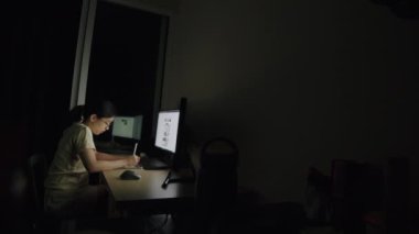 Asyalı iş kadınının açık sözlülüğü, ev ofisinin birinde bir tablete iş yazma, haber yayınlarını kaydırma ve çalışma planı için çevrimiçi bilgi arayışı.