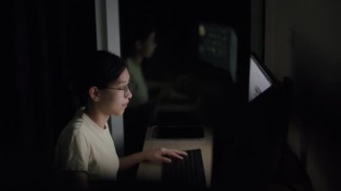 Geceleri evde bilgisayarla çalışan Asyalı bir kadın internetten öğrenen mutlu bir kız ve internetten bir şeyler satın alıyor..