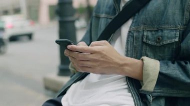 Şehirdeki bir bankta otururken akıllı telefon kullanarak sosyal medyayı kontrol eden Asyalı adamı kapat..