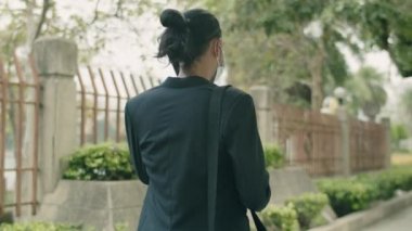 Kentteki covid-19 salgını sırasında kentte yürürken elinde kahve fincanı ve sohbet telefonu tutan kendine güvenen Asyalı işadamı..