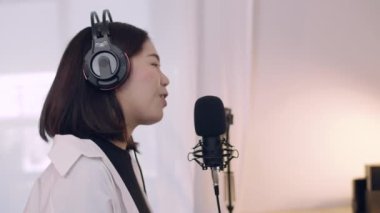 Güzel genç Asyalı kadın nüfuzlu biri bir podcast kaydederken mikrofona konuşuyor ve sosyal medya için canlı yayın içeriği.