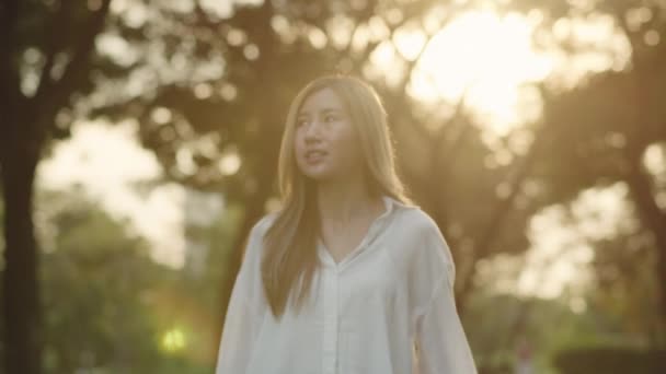 日落时分 一位美丽的年轻亚洲女子在公园里享受着轻风森林的美景 — 图库视频影像