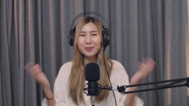 Güzel genç Asyalı kadın etkileyicisi, sosyal medya için podcast mikrofon kullanarak bir vlog kaydediyor ve canlı yayın içeriğini sosyal medya için kaydediyor..