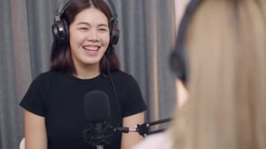 Podcast 'leri kaydederken ve stüdyoda canlı yayın yaparken iki genç Asyalı kadın podcaster sohbeti..