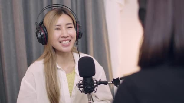 スタジオの職場でポッドキャストやライブストリーミングを記録しながら 2つの若いアジアの女性ブロガーの会話 — ストック動画