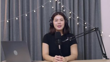 Güzel Asyalı kadın etkileyicisi, sosyal medya için podcast mikrofon kullanarak bir vlog kaydediyor ve canlı yayın içeriğini kaydediyor..