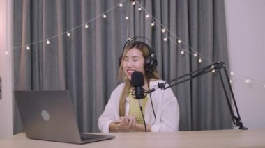 Güzel Asyalı kadın etkileyicisi sosyal medya için podcast mikrofon kullanarak bir vlog kaydediyor ve podcast canlı yayın içeriğini kaydediyor.