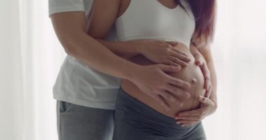 Yakın plan mutlu Asyalı koca hamile bir eş karnını tutuyor ve yatak odasındaki samimi dansın tadını çıkarıyor..