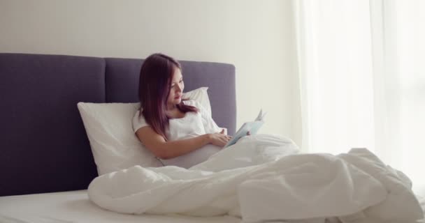 Mutlu Asyalı Hamile Doğmamış Bir Çocuğa Kitap Okurken Yatak Odasında — Stok video