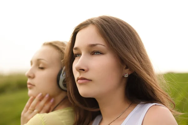Duas meninas felizes ouvindo música no parque de verão — Fotografia de Stock