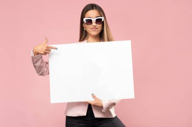 Mutlu genç kadın elinde beyaz bir poster tutuyor..