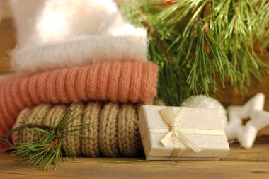 Mutlu yıllar, tahta arka planda beyaz bir kutuda hediye sıcak kazaklar ve ladin dallarıyla..