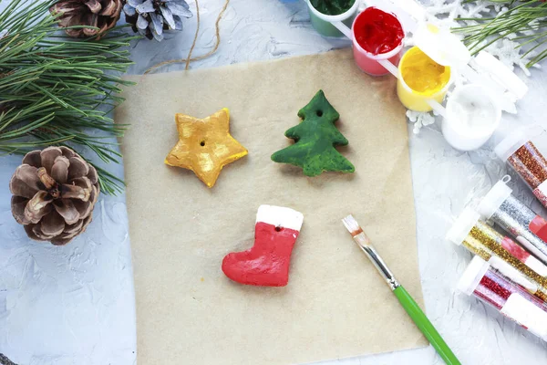 Un pinceau avec de la peinture rouge peint une chaussette de Noël, jouets bricolage pour la nouvelle année, décoration créative pour un arbre de Noël en pâte de sel — Photo