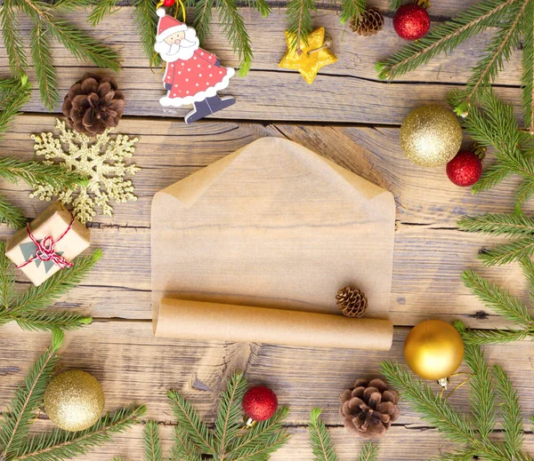 Mensaje sobre maqueta de papel artesanal en el centro de un círculo hecho de decoraciones navideñas y ramas de un árbol de Navidad sobre un fondo de madera. — Foto de Stock