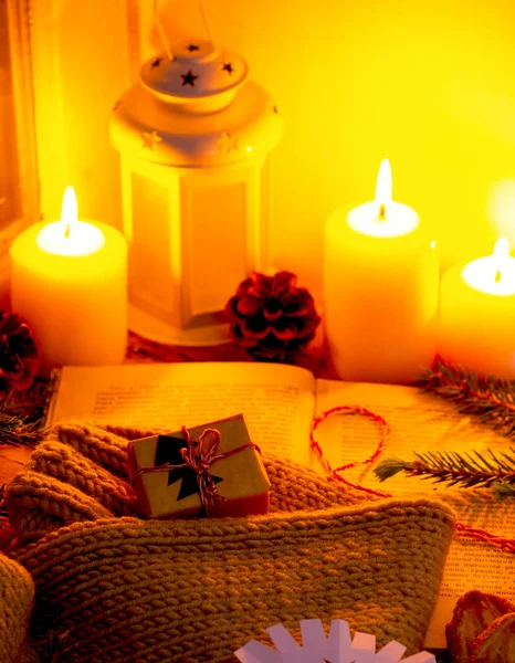 Composición de una acogedora noche de Navidad en la ventana con velas, un regalo y un suéter caliente — Foto de Stock
