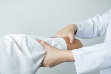 Kadın fizyoterapistler, erkek hastalara omuz sakatlığı olan hastalar için rehabilitasyon merkezinde omuzlarına masaj yapıyorlar. Fizyoterapi kavramları.