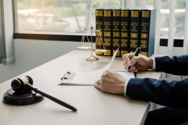 Profesyonel erkek avukatlar bir hukuk bürosunda çalışır. Teraziler, adalet terazileri, yargıç tokmağı ve dava belgeleri vardır. Hukuk ve adalet kavramları.