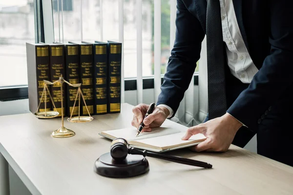 Profesyonel erkek avukatlar bir hukuk bürosunda çalışır. Teraziler, adalet terazileri, yargıç tokmağı ve dava belgeleri vardır. Hukuk ve adalet kavramları.