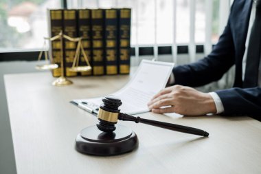 Profesyonel erkek avukatlar bir hukuk bürosunda çalışır. Teraziler, adalet terazileri, yargıç tokmağı ve dava belgeleri vardır. Hukuk ve adalet kavramları.