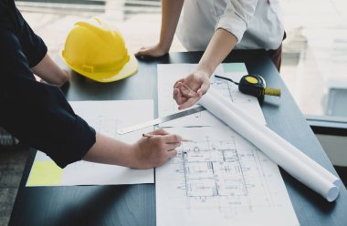 Mühendisler ve mimarlardan oluşan bir ekip, çalışma ekibi, toplantı, inşaat planları ve çizim planları, baskı, inşaat alanlarında yazma konuları. Ev tasarımı kavramı.