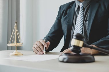 Profesyonel erkek avukatlar bir hukuk bürosunda çalışır. Teraziler, adalet terazileri, yargıç tokmağı ve dava belgeleri vardır. Hukuk ve adalet kavramları.