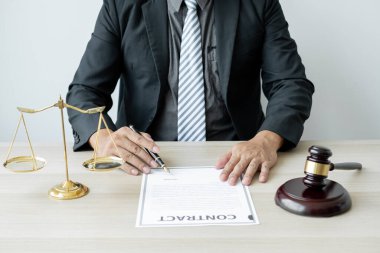Profesyonel erkek avukatlar bir hukuk bürosunda çalışır. Teraziler, adalet terazileri, yargıç tokmağı ve dava belgeleri vardır. Hukuk ve adalet kavramları.