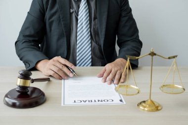 Profesyonel erkek avukatlar bir hukuk bürosunda çalışır. Teraziler, adalet terazileri, yargıç tokmağı ve dava belgeleri vardır. Hukuk ve adalet kavramları.