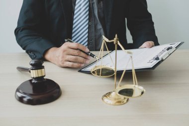 Profesyonel erkek avukatlar bir hukuk bürosunda çalışır. Teraziler, adalet terazileri, yargıç tokmağı ve dava belgeleri vardır. Hukuk ve adalet kavramları.