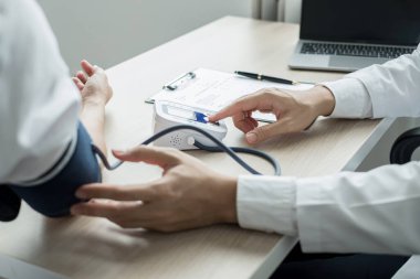 Erkek doktorlar kan basıncını ölçtü, hasta kalp atışlarını inceledi ve sağlık hizmetleri hakkında yakından konuştu. Tıbbi ve sağlık hizmetleri kavramları.