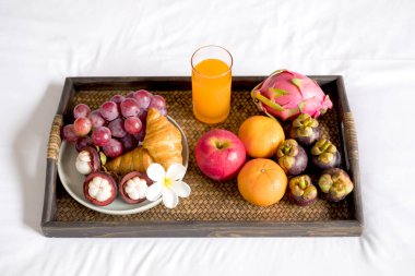 Meyveye odaklan. Meyveli bir otel odasında, VIP misafirlerin gelişini karşılamak için yatağın üzerine bir tepsi koyun..