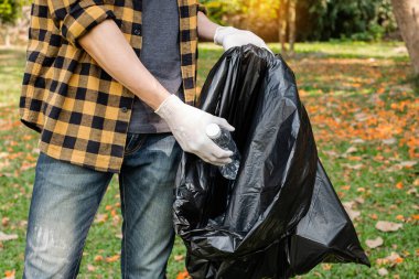 Adamın elleri plastik şişeleri topluyor, çöpleri siyah çöp torbalarına doldurup parkları temizliyor, kirlilikten kaçınıyor, çevreye ve ekosisteme dost oluyor..