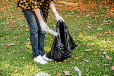 Adamın elleri plastik şişeleri topluyor, çöpleri siyah çöp torbalarına doldurup parkları temizliyor, kirlilikten kaçınıyor, çevreye ve ekosisteme dost oluyor..