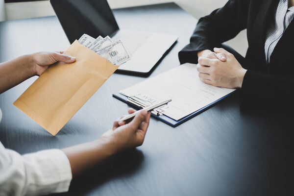 Бизнесмены заключают соглашение с деньгами, предложенными его партнером для подкупа в компании. Концепция взяточничества и коррупции.