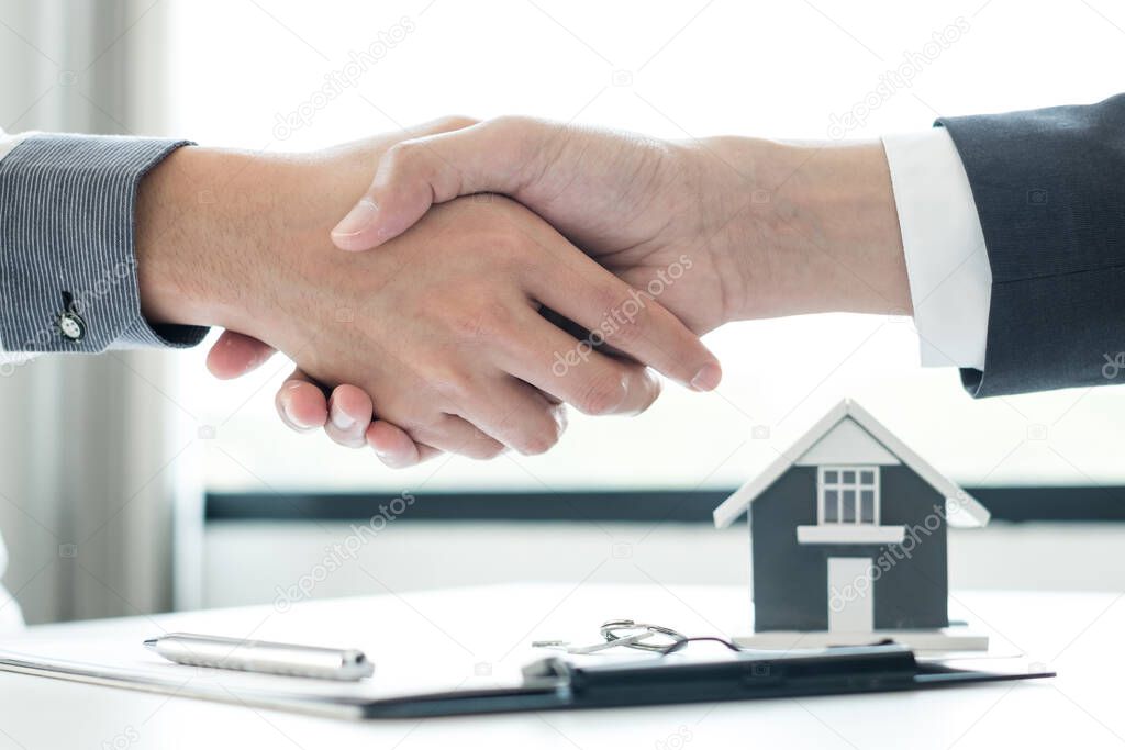 Businessmen and brokers' real estate agents shake hands after completing negotiations to buy houses insurance and sign contracts. Home insurance concept.