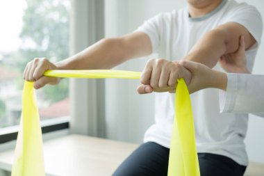 Kadın fizyoterapistler, tedavi merkezinde kol yaralanması, kol çekme ve kas gevşemesi olan erkek hastalara yardım ediyorlar. Fizyoterapi kavramları.