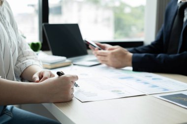 İki iş lideri çizelgeler, finansal grafikler hakkında konuşuyor. Sonuçları gösteren planlama stratejilerini analiz ediyor ve hesaplıyor. Ticari başarı oluşturma süreçlerini de..